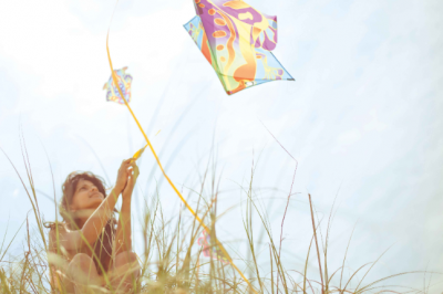 A beautiful Indian woman flying a kite from the top of a hill on a beautiful summery day at the beach in North carolina.